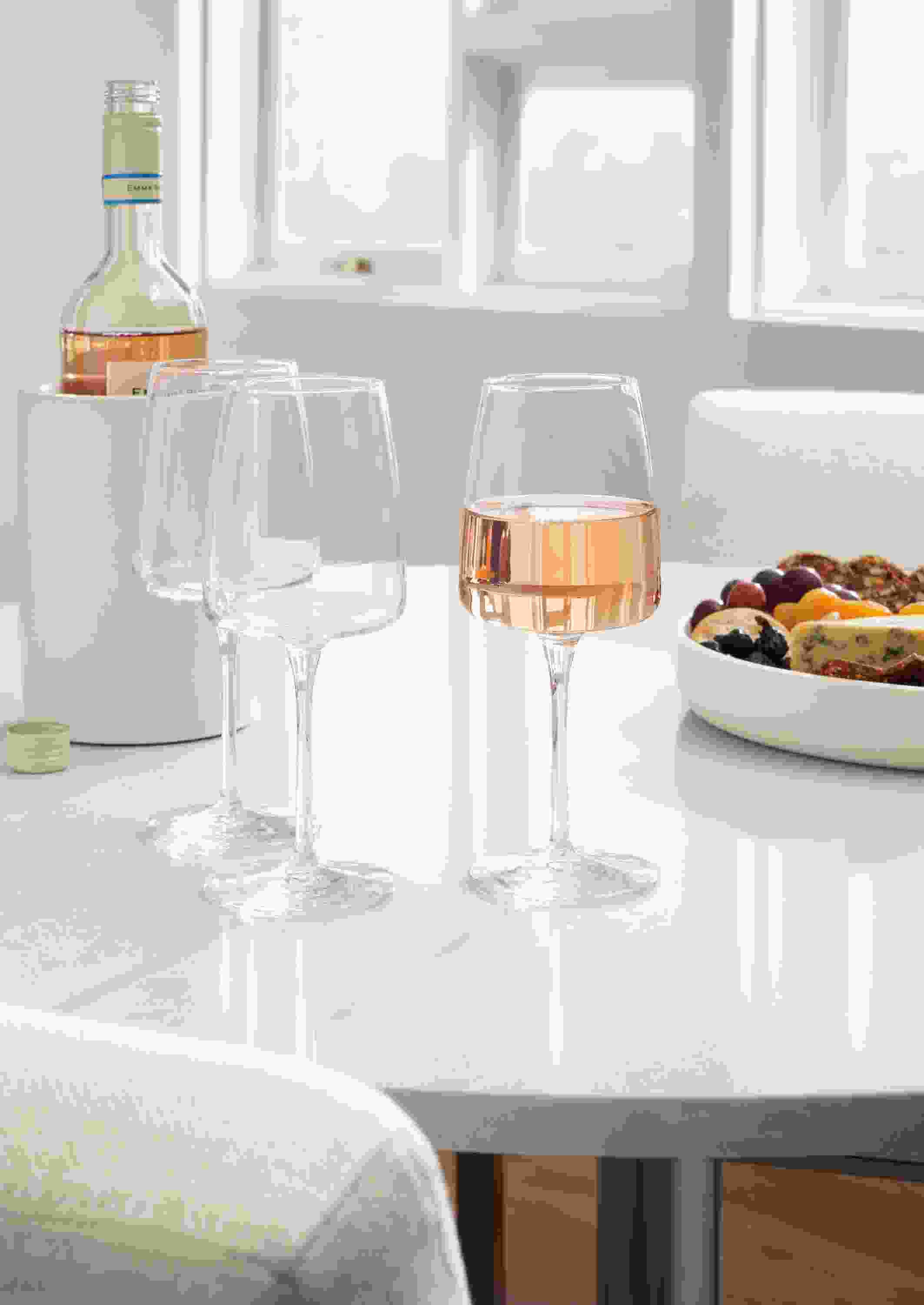 Detail of 3 vine wine glasses on white aria table with light grey quartz top.