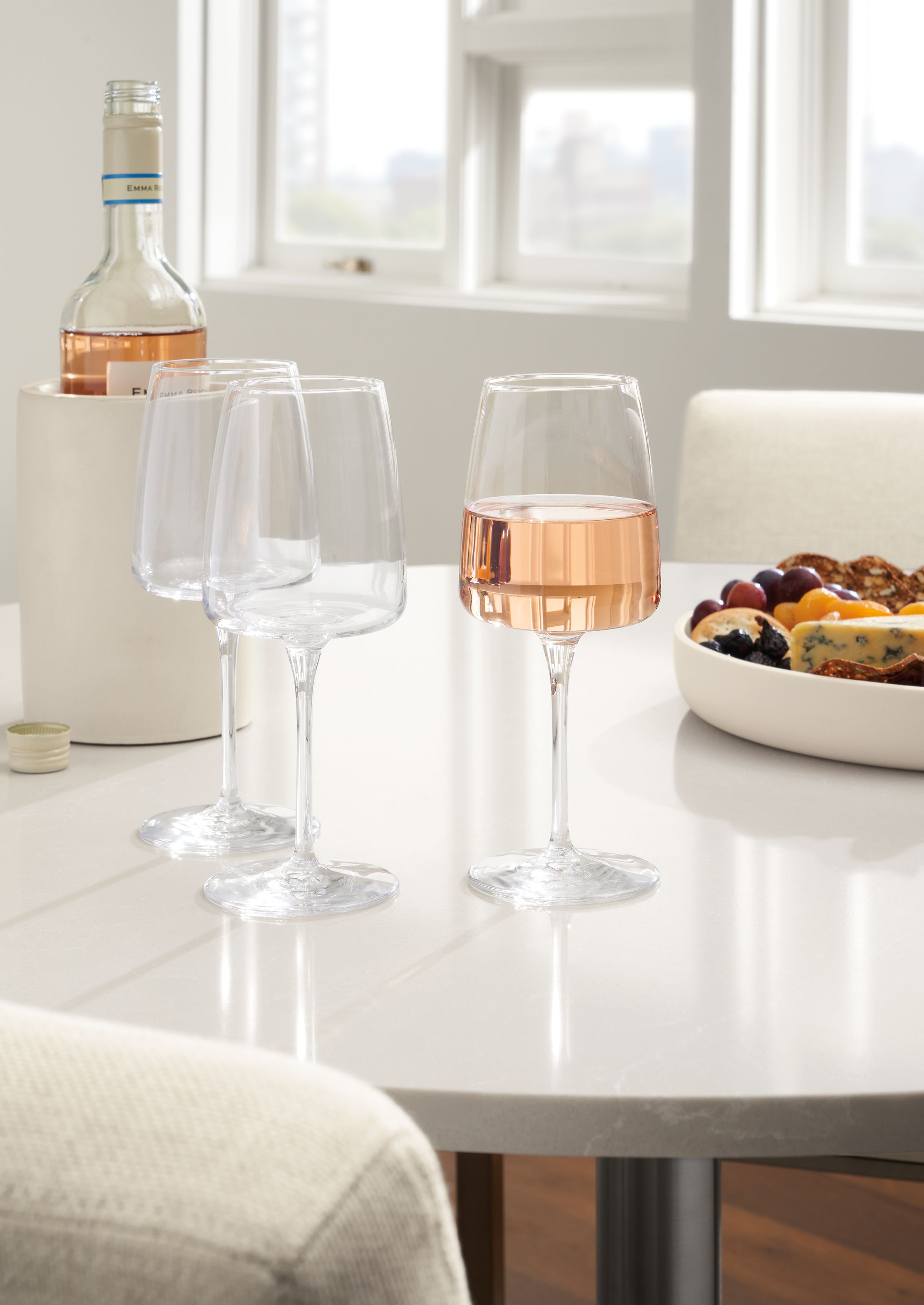 Detail of 3 vine wine glasses on white aria table with light grey quartz top.