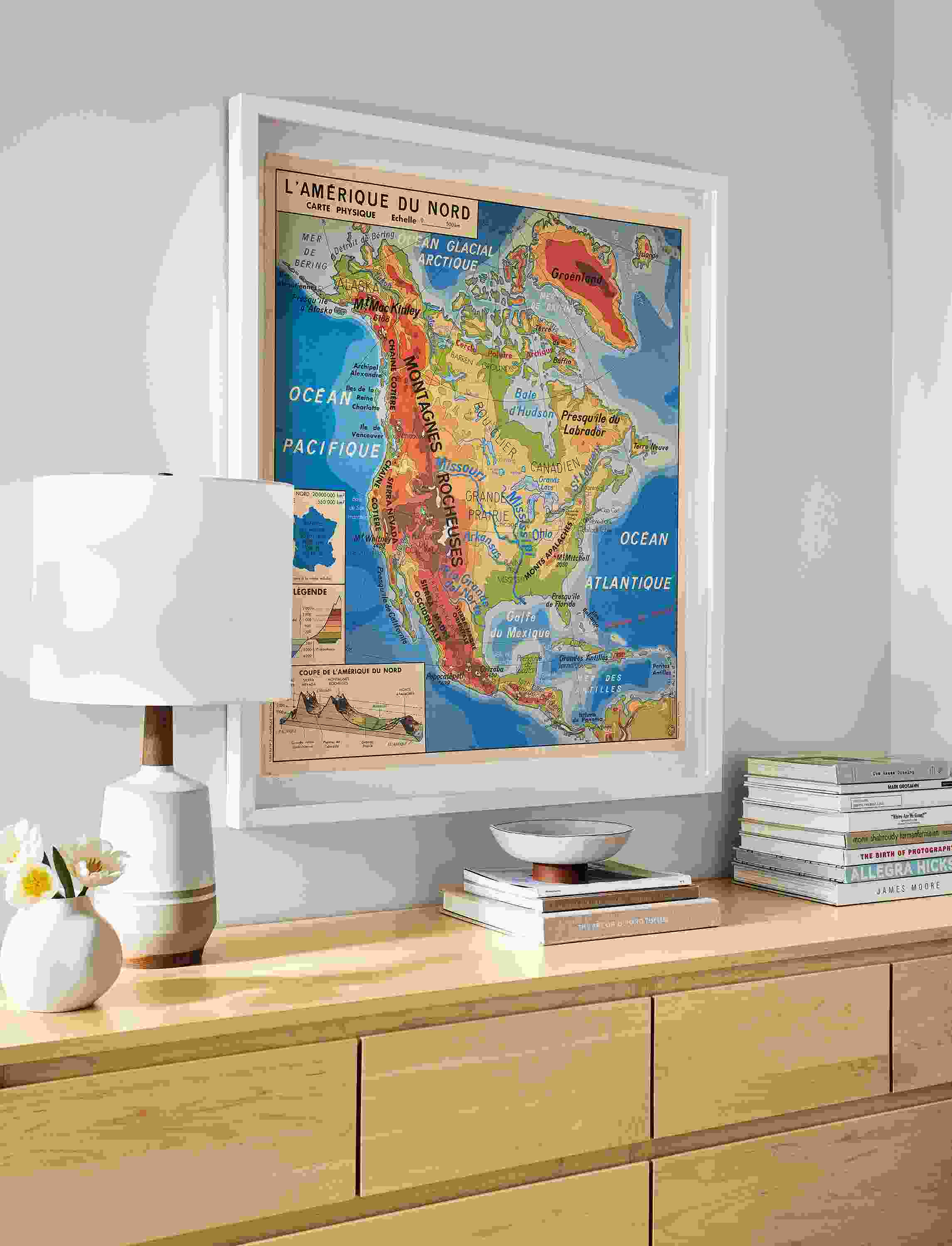 Close-up of vintage medium vertical French school map with white frame and Arrow ten-drawer dresser in maple.