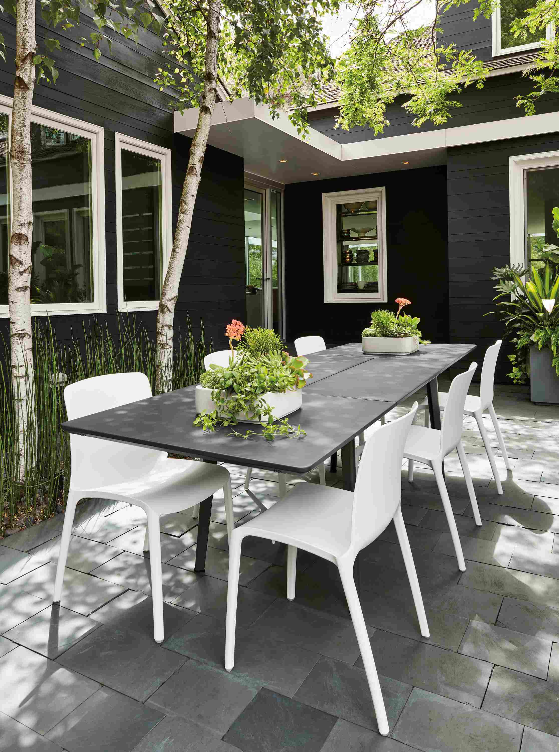 Detail of Vista outdoor extension table in graphite in extended view with 6 Tiffany side chairs in white.