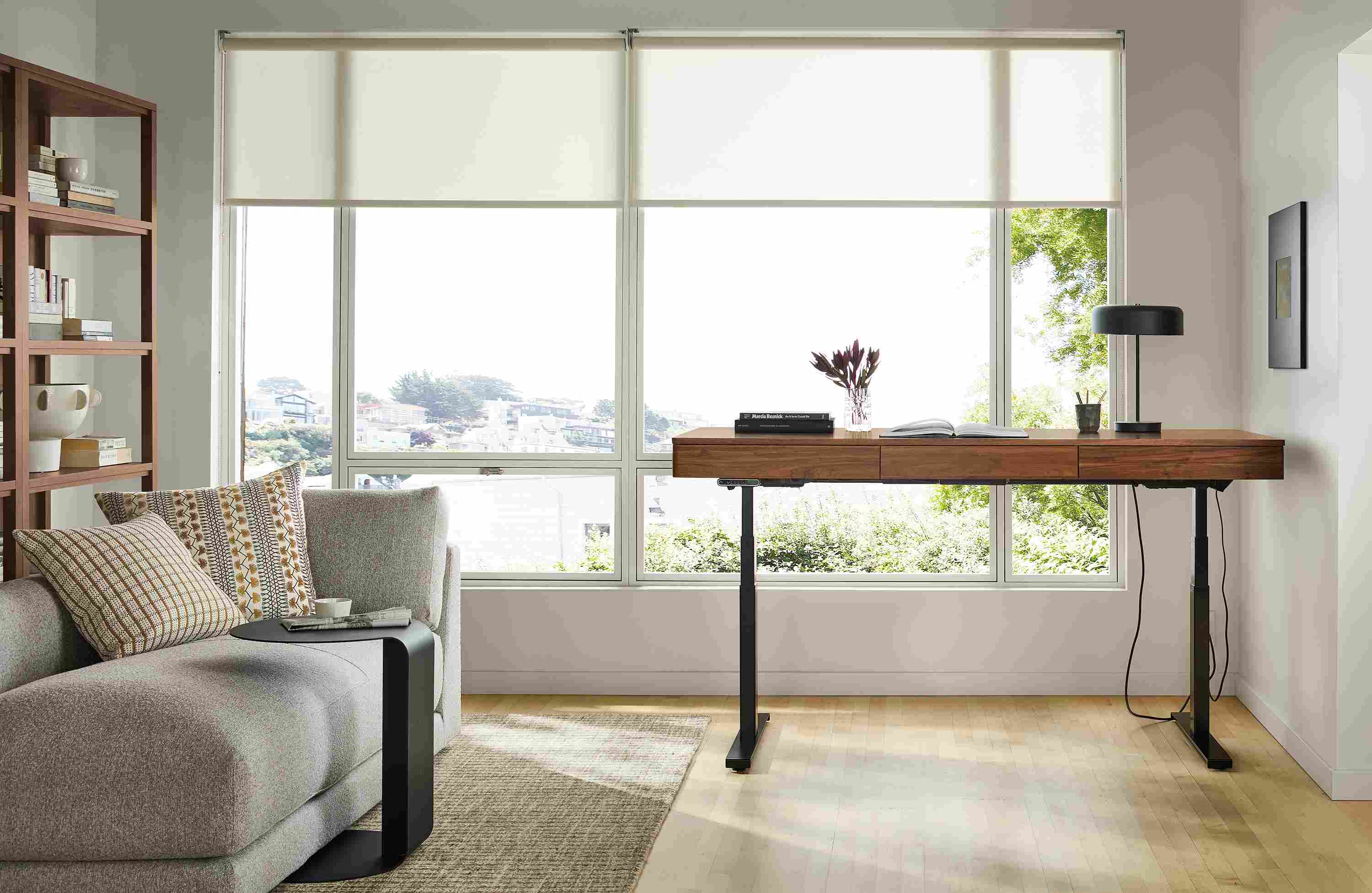 Home office with a raised Wade adjustable standing desk in walnut and Nera rug in stone.