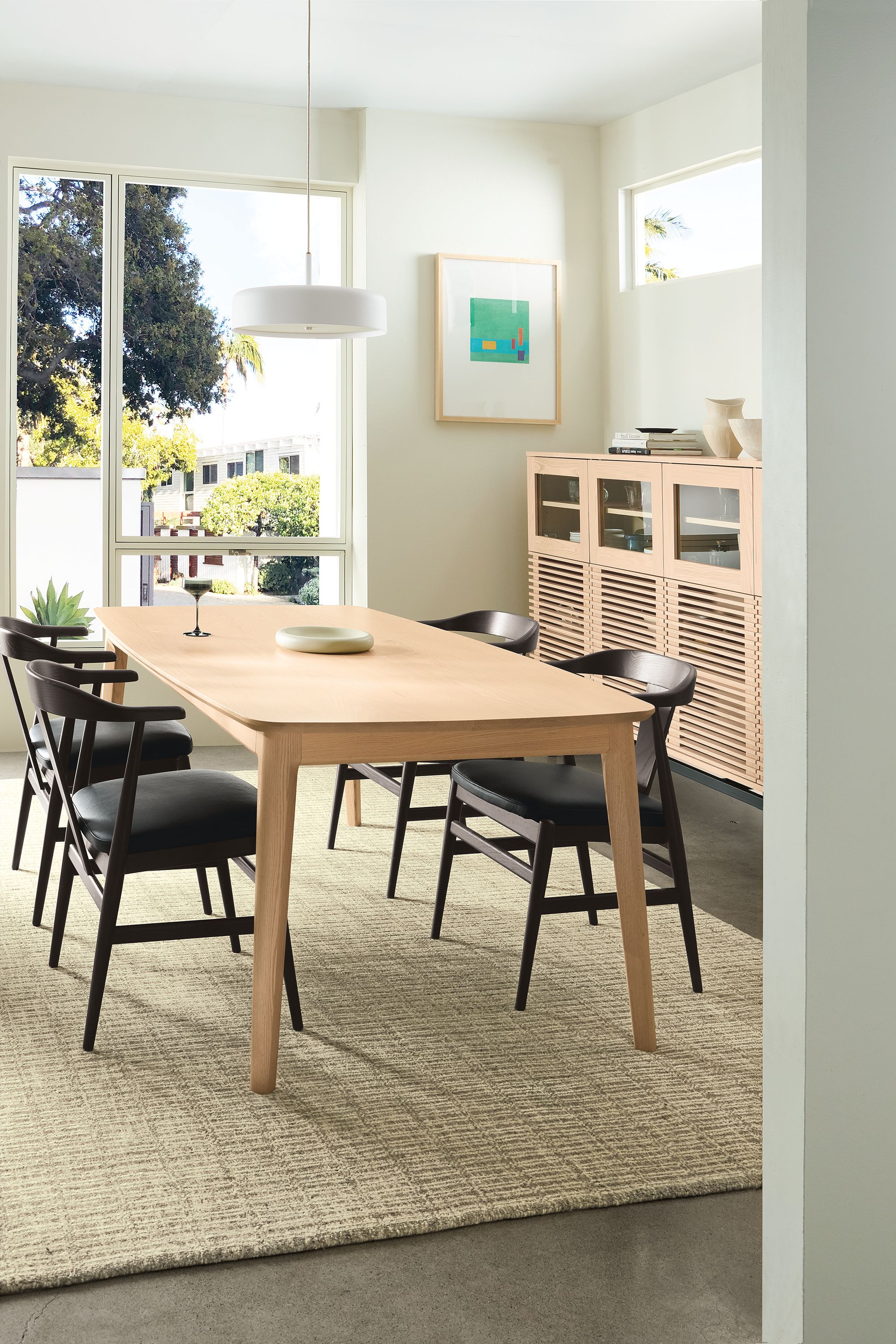 Dining room with Walcott 75-wide table in salt on red oak, 4 Evan arm chairs in charcoal and Pesaro Black leather and Nera rug.