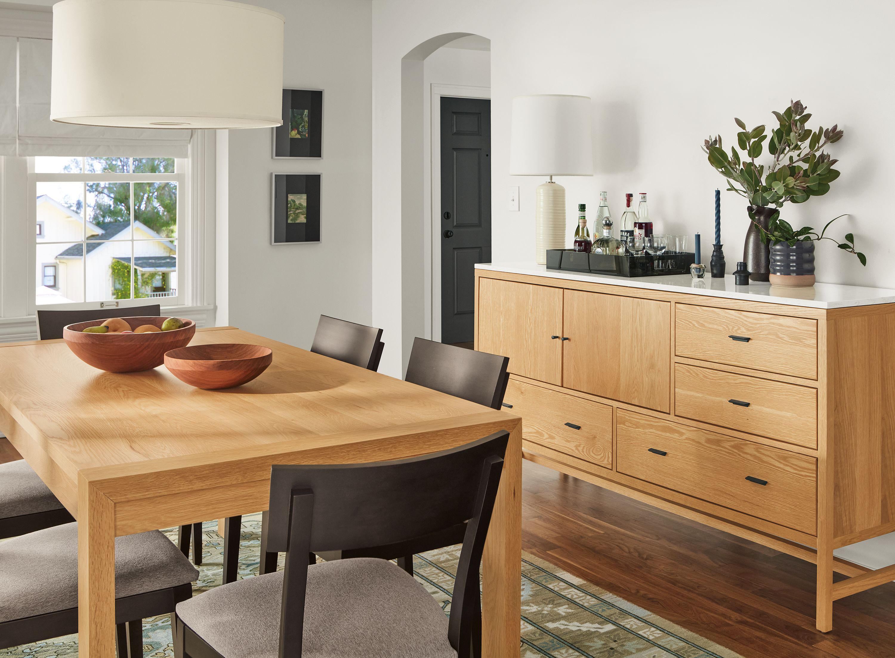 Dining area with Walsh 72-wide dining table and Berkeley 72-wide storage cabinet with quartz top in White oak and Doyle chairs.