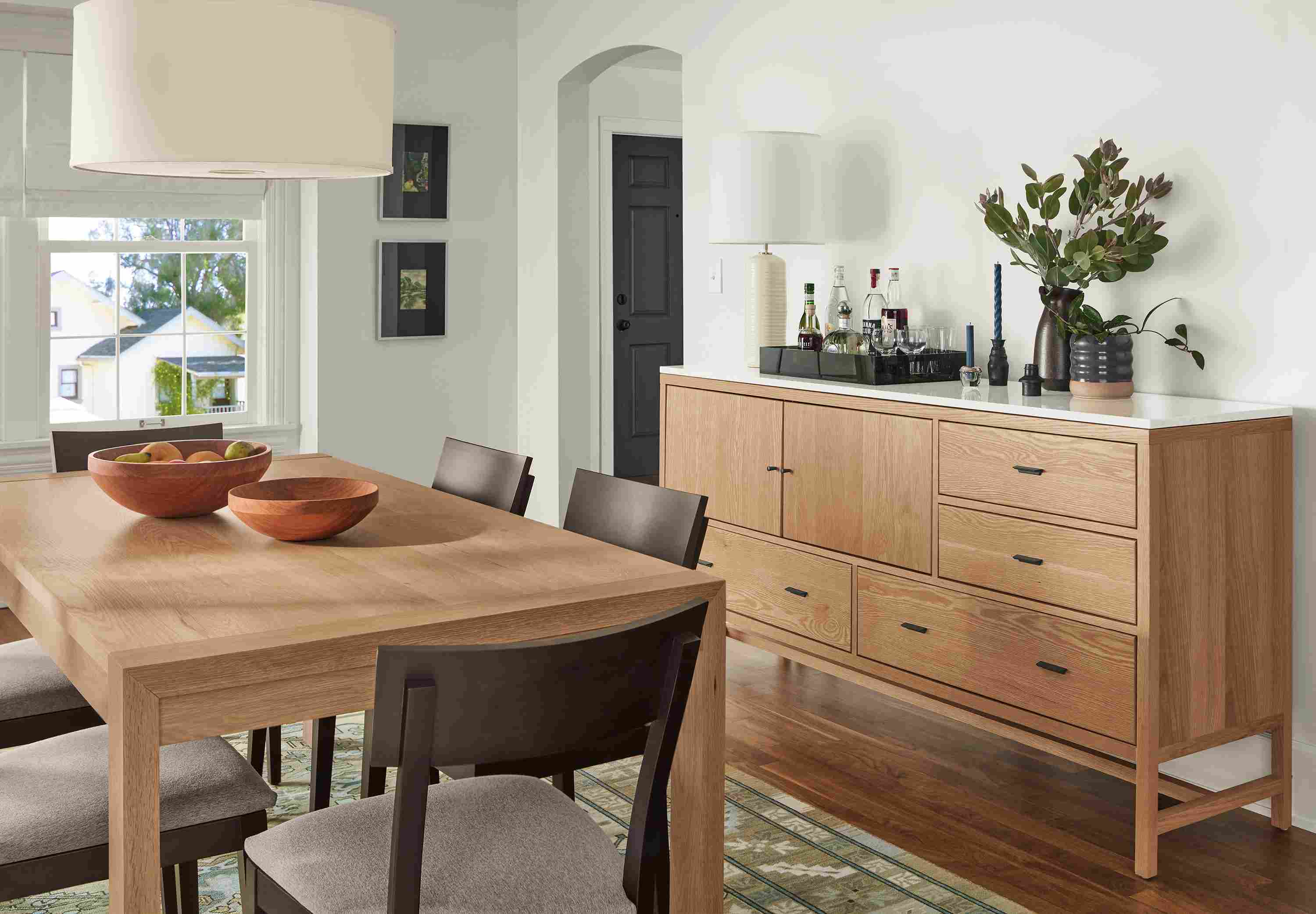 Dining area with Walsh 72-wide dining table and Berkeley 72-wide storage cabinet with quartz top in White oak and Doyle chairs.