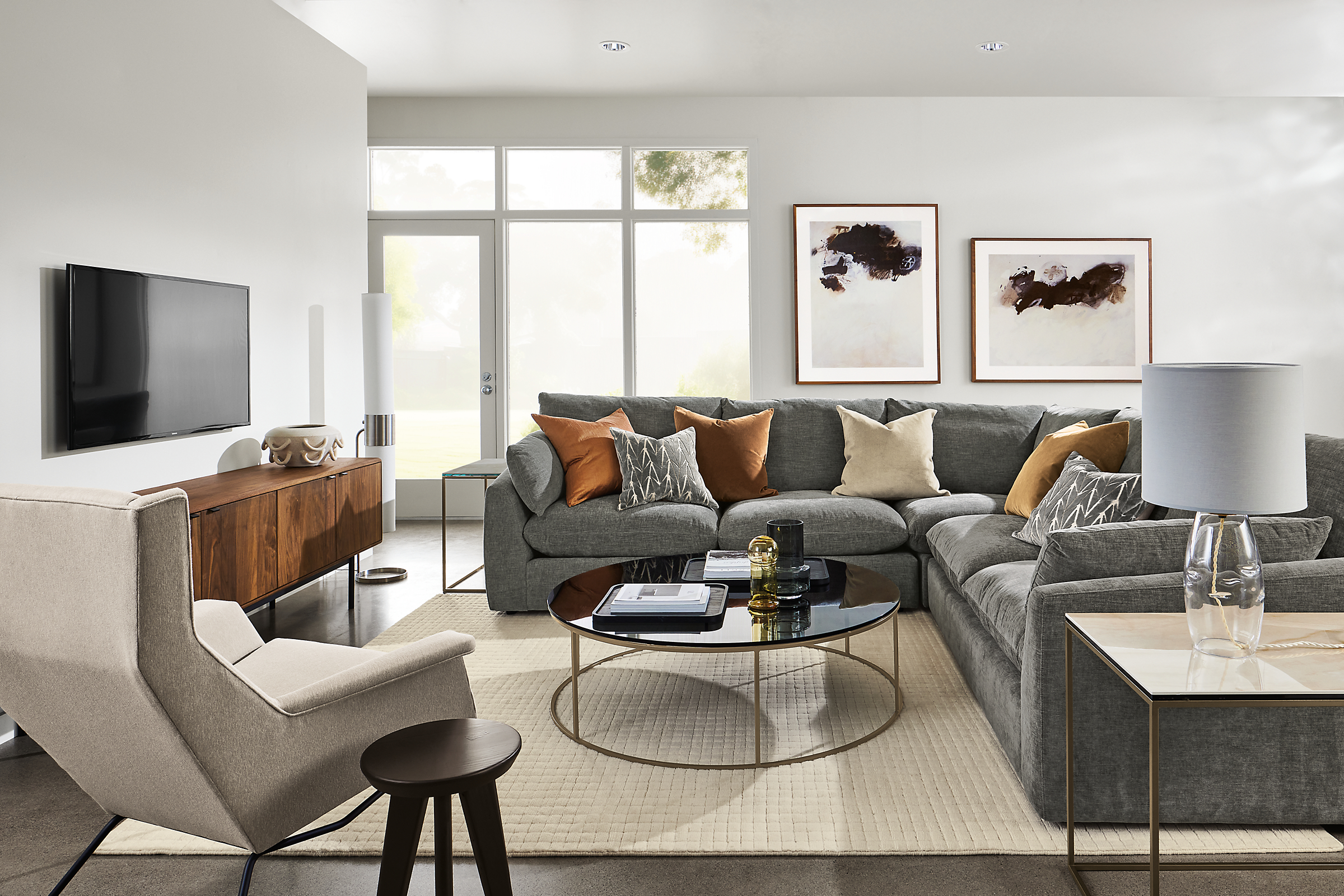 Living roon with weber sectional in mori graphite fabric, aidan chair, type coffee and end tables and hensley media cabinet.