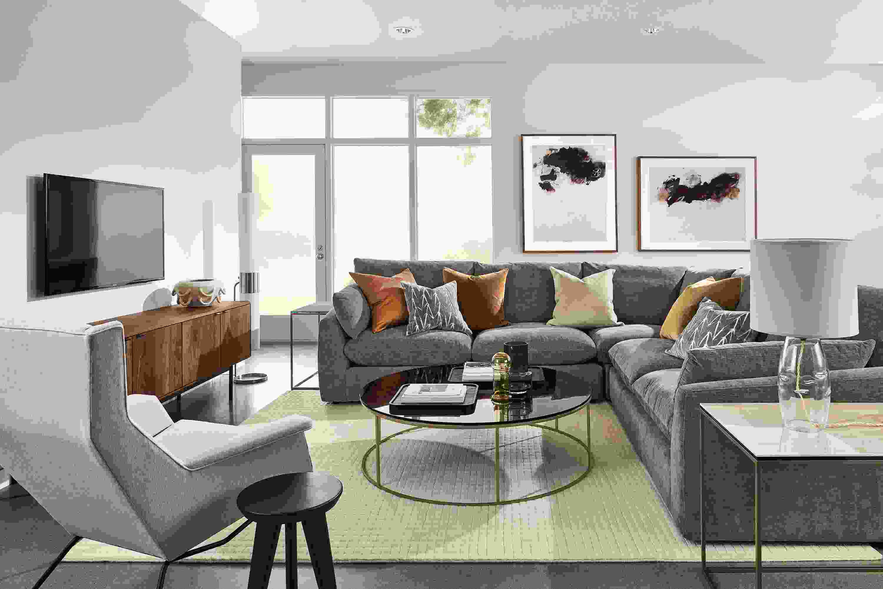 Living roon with weber sectional in mori graphite fabric, aidan chair, type coffee and end tables and hensley media cabinet.