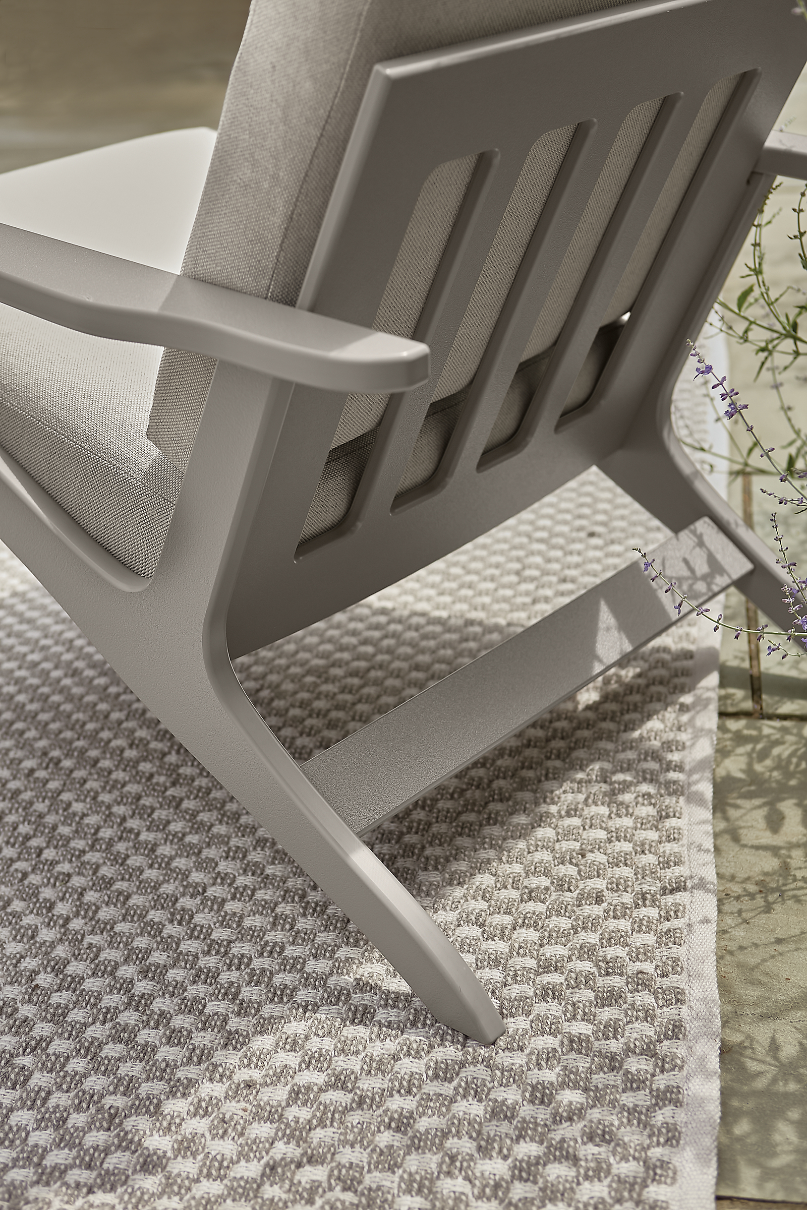detail of back of breeze chair on weldon rug in outdoor space.
