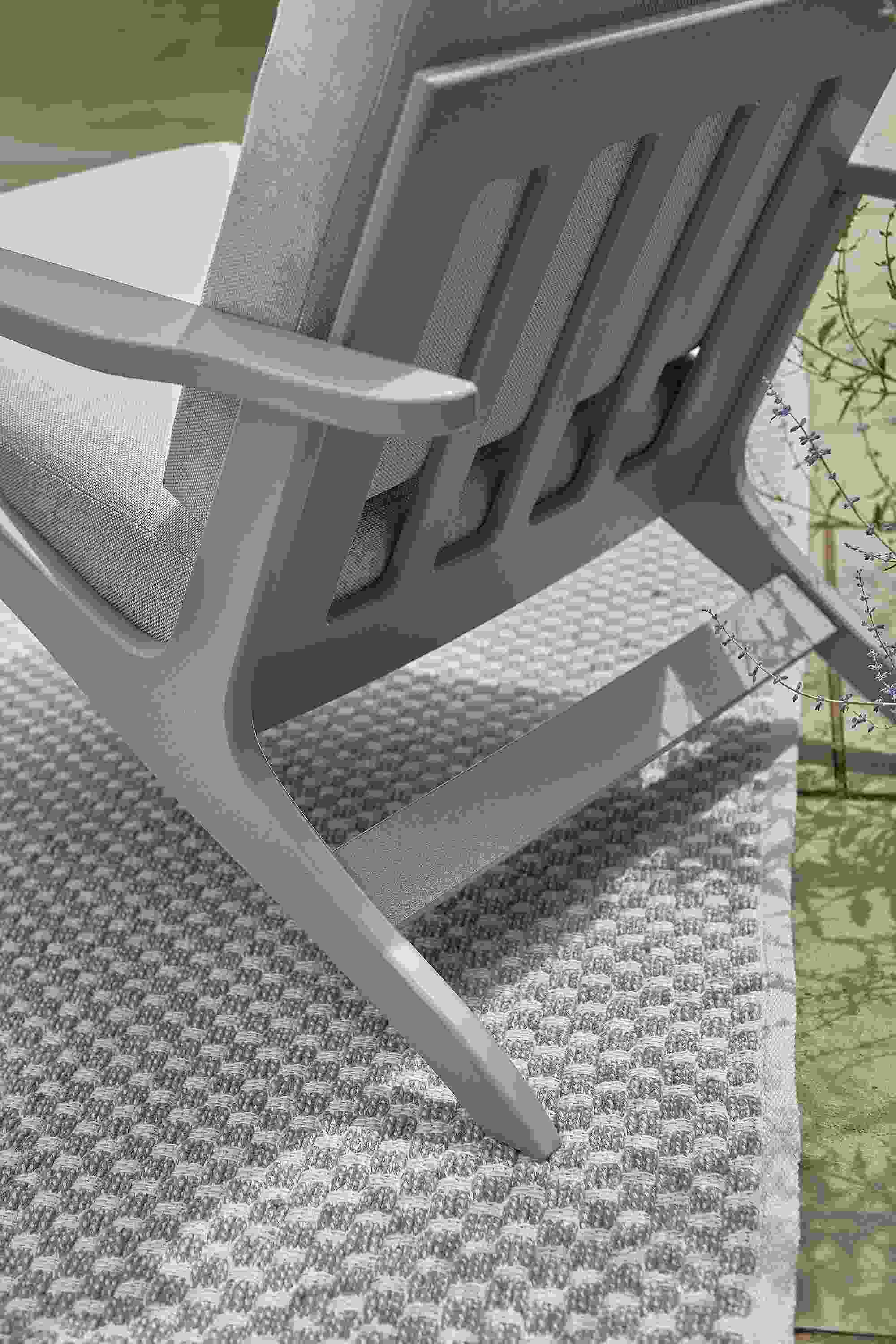 Detail of back of a  breeze chair in grey on Weldon rug in putty on a patio.