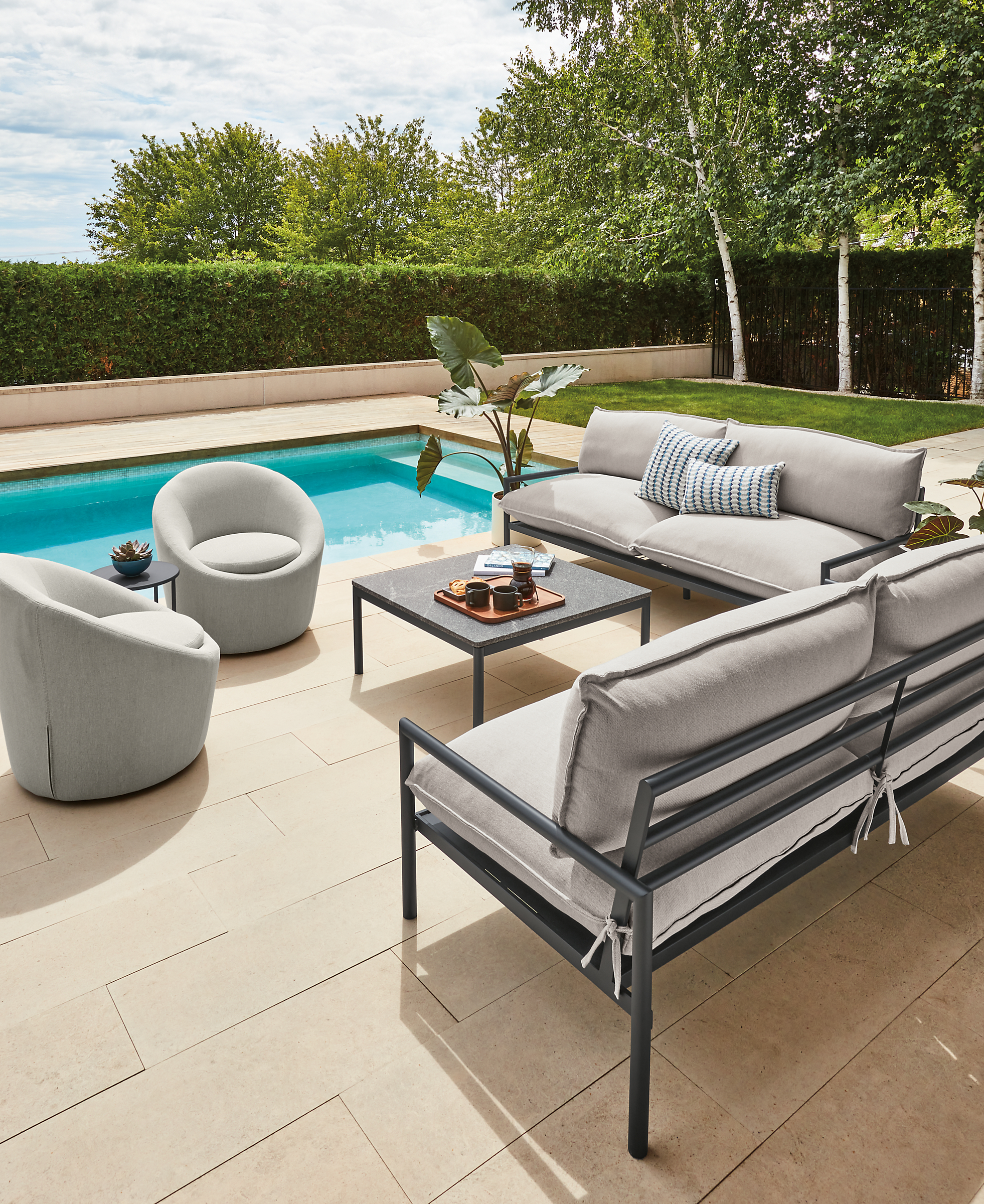 Two Westbrook outdoor sofas in graphite with Mist grey cushions, two Crest swivel chairs and Westbrook coffee table with Elegant grey granite top.