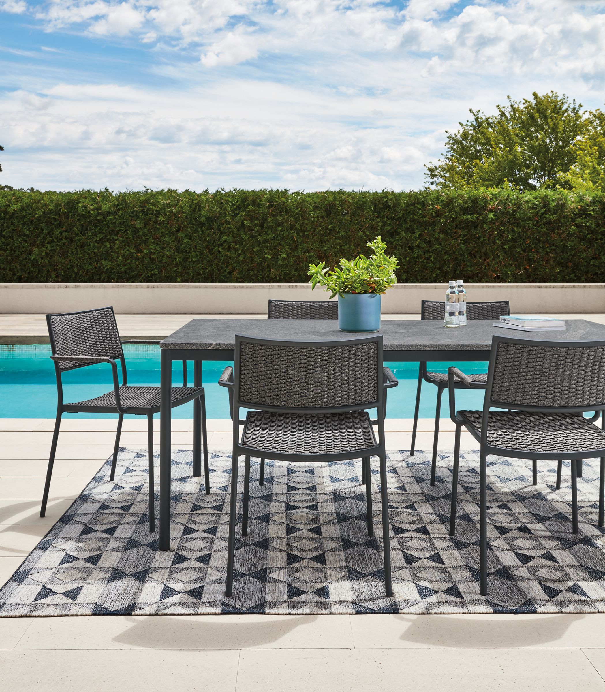Westbrook outdoor dining table in graphite with Elegant grey granite top and Plat chairs in slate with graphite frame.