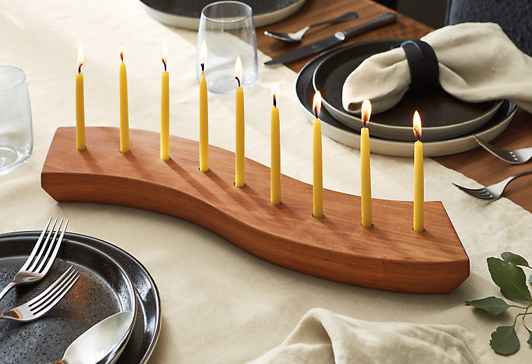 tabletop with winding menorah in cherry with hanukkah candles inserted.
