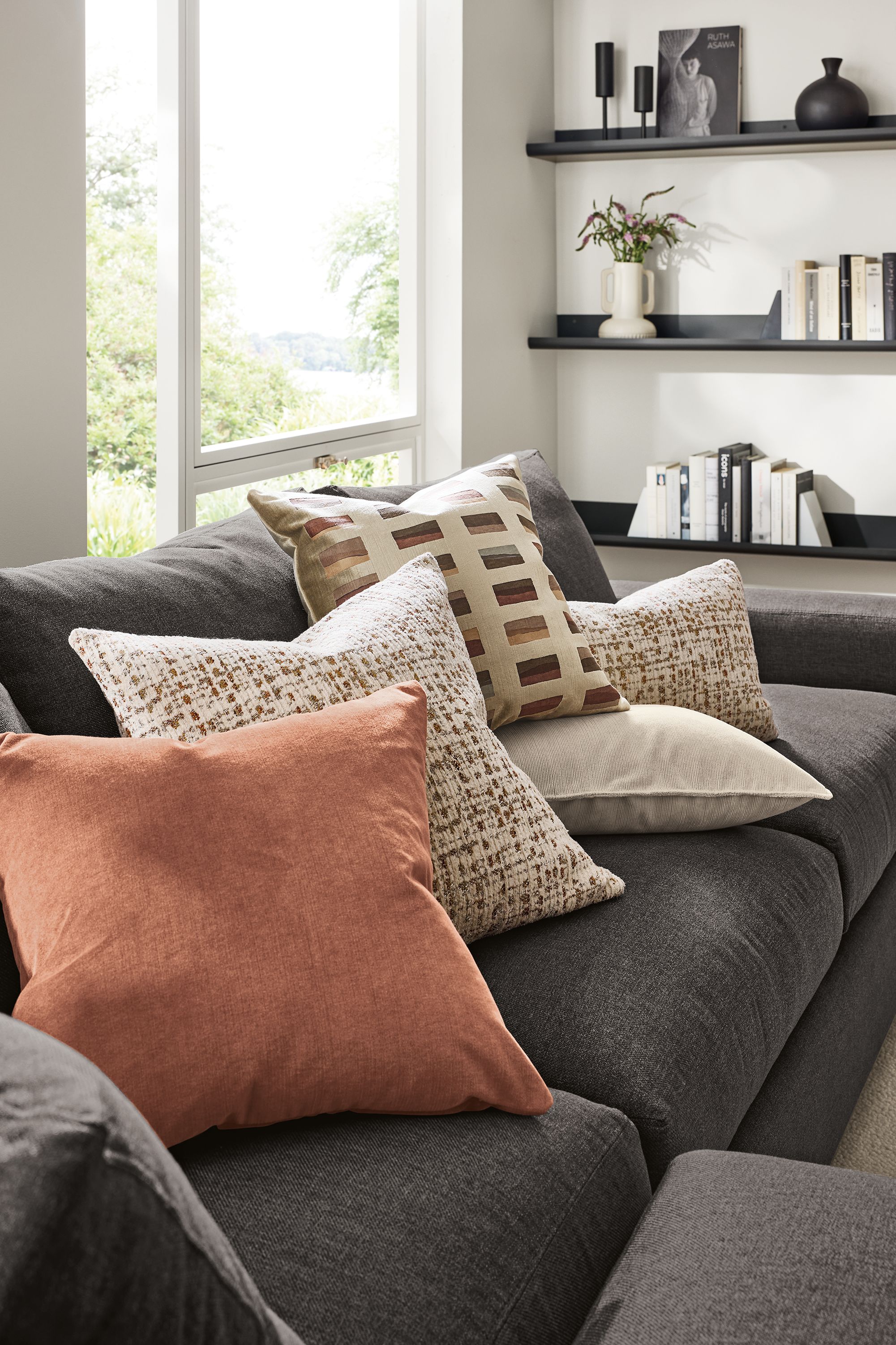 A collection of throw pillows including windsor velvet in clay, tromso in rust, capa in merlot, nigel in natural and tromso in rust on a metro sofa.