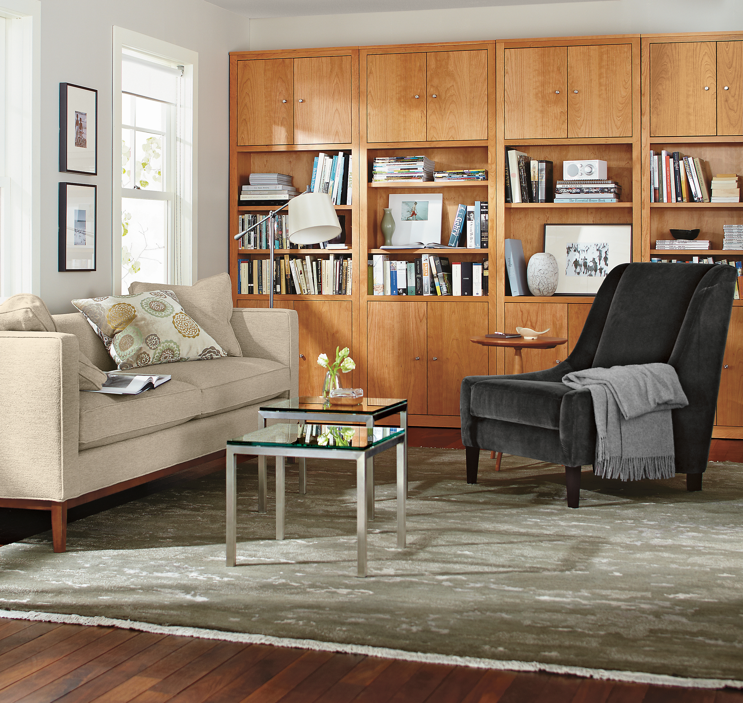 room setting including woodwind bookcases, maddox sofa, audrey chair, shadow rug, zinnia pillow.