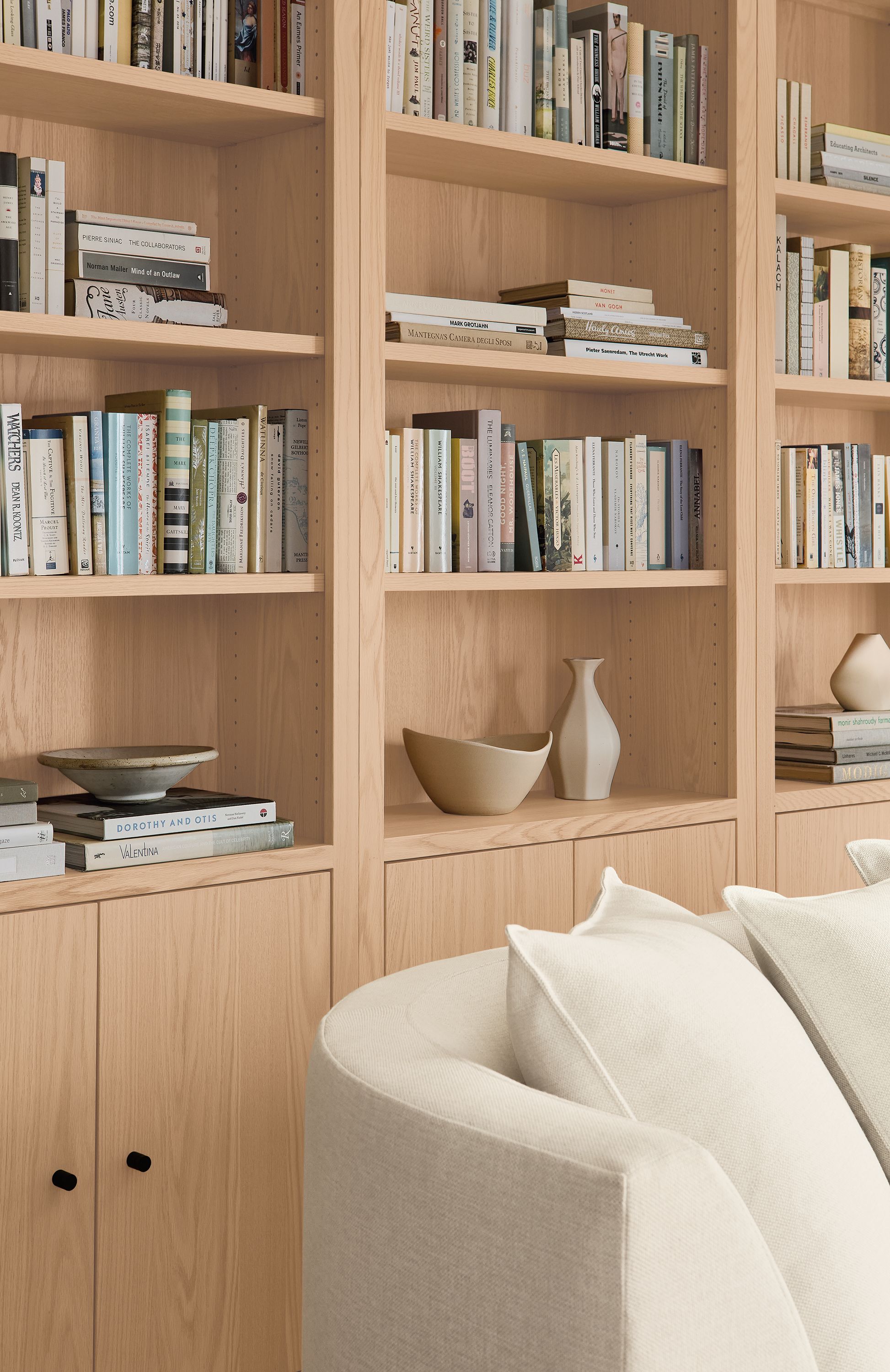 Detail of 3 Woodwind 32-wide two-door bookcase in salt on red oak and astaire 90-wide sofa in sumner ivory.