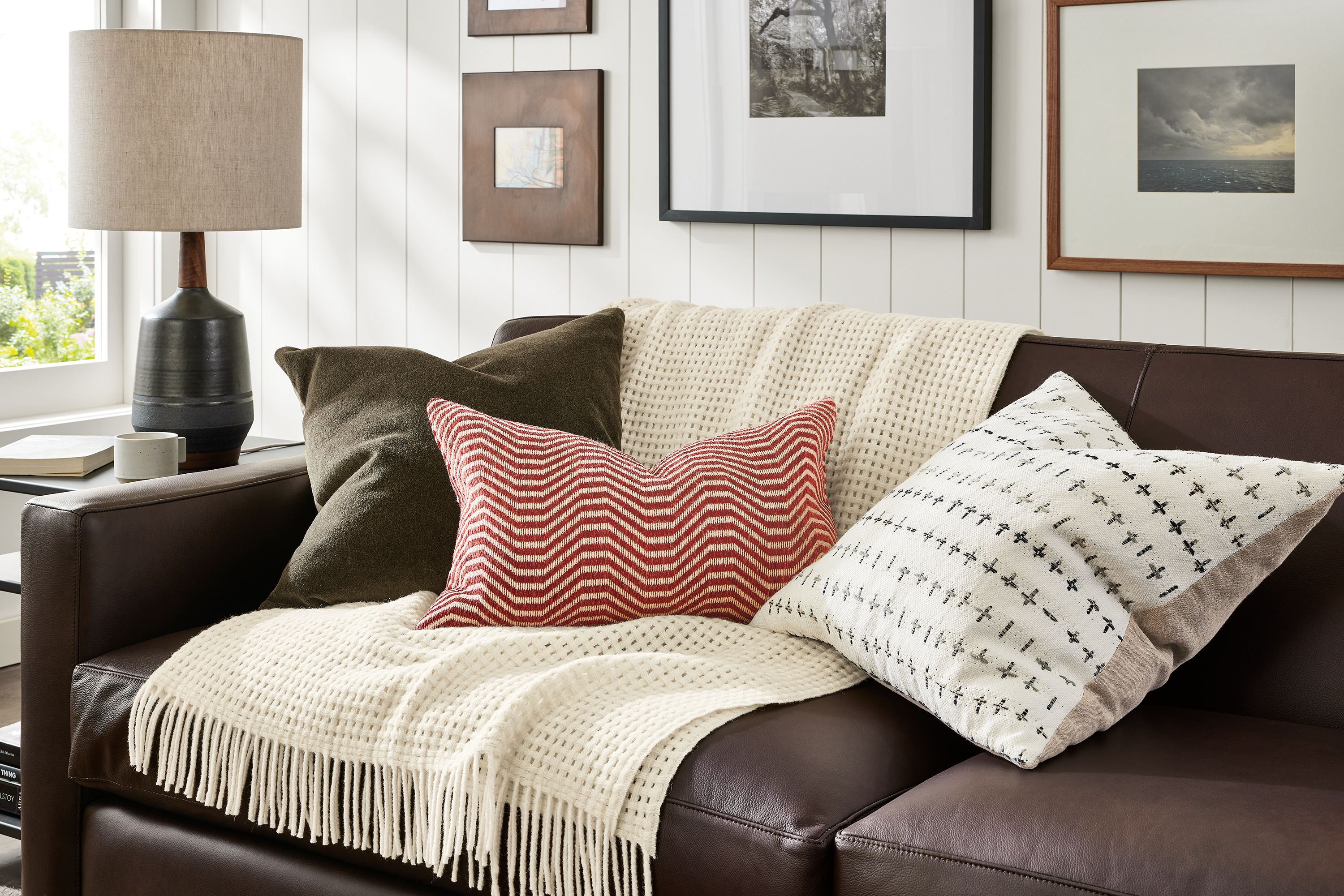 Living room with pillows in wool velvet mink, Lines rust, Savone in Ivory and Homage throw in Ivory on Alex sofa.