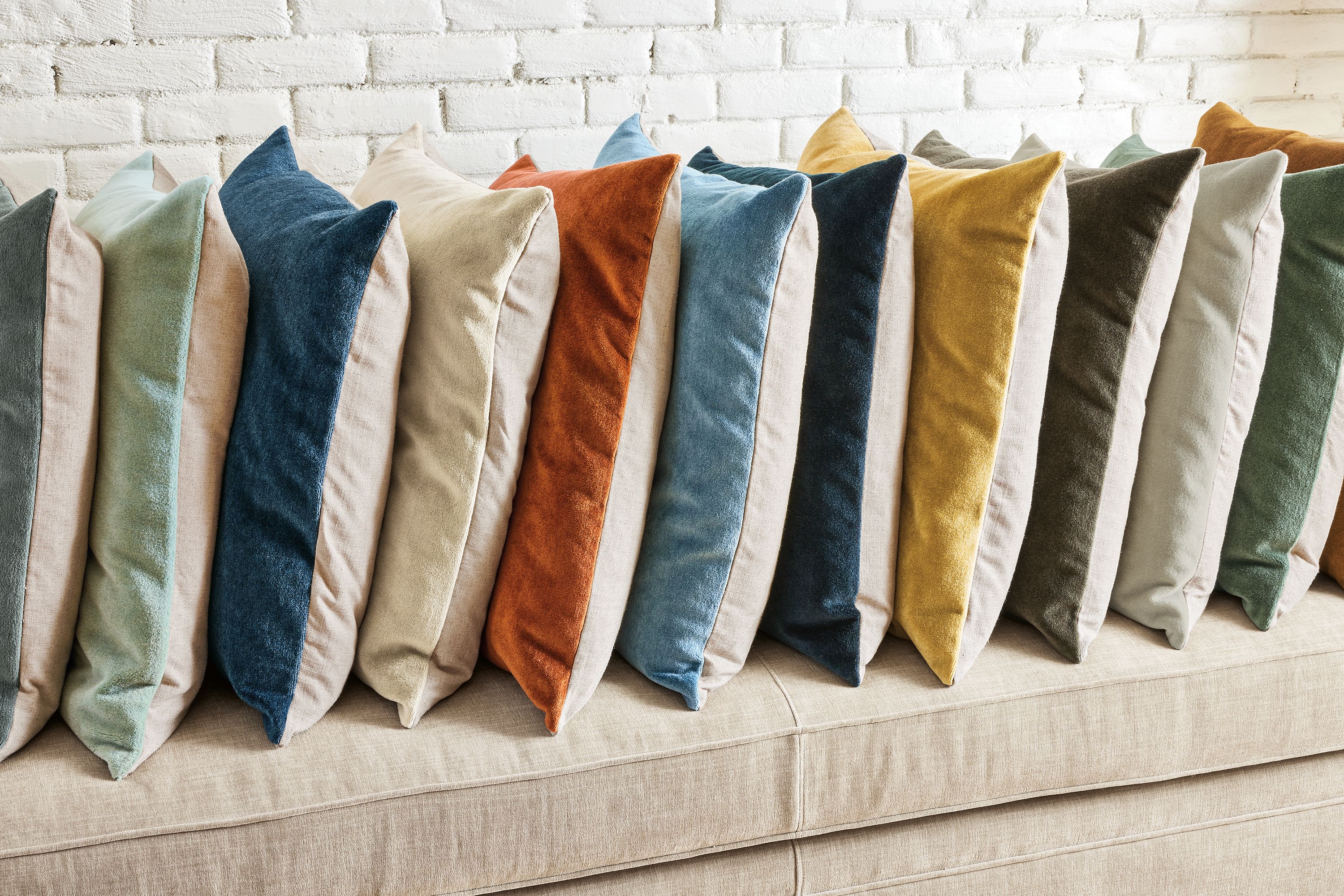 A row of wool velvet pillows of various colors on a Macalester sofa.