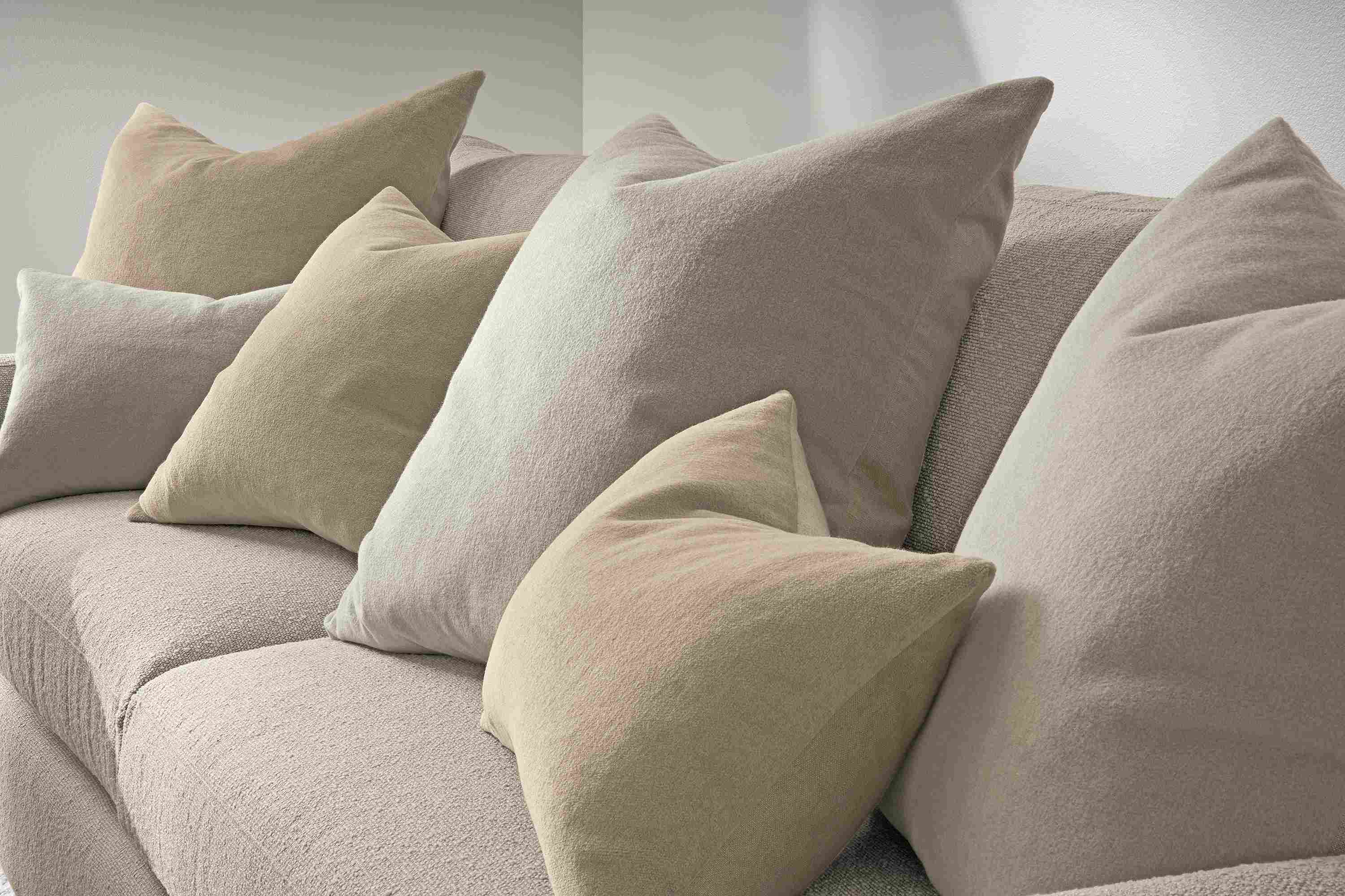 Detail of a group of  wool velvet pillows in grey and sand on a Linger sofa in Declan Natural fabric.