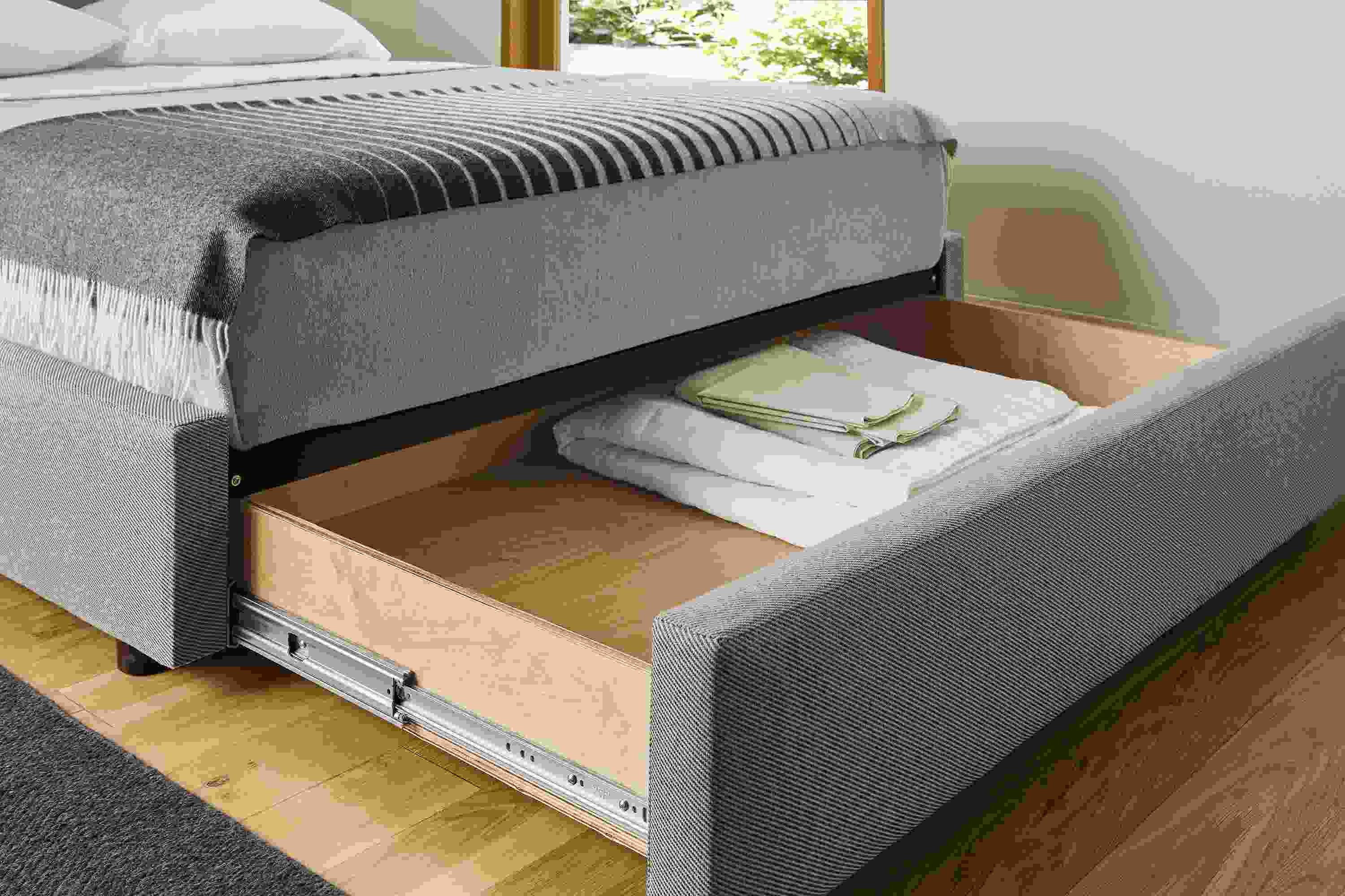 Bedroom with detail of wyatt queen storage bed in derry cement shown with storage drawer open.