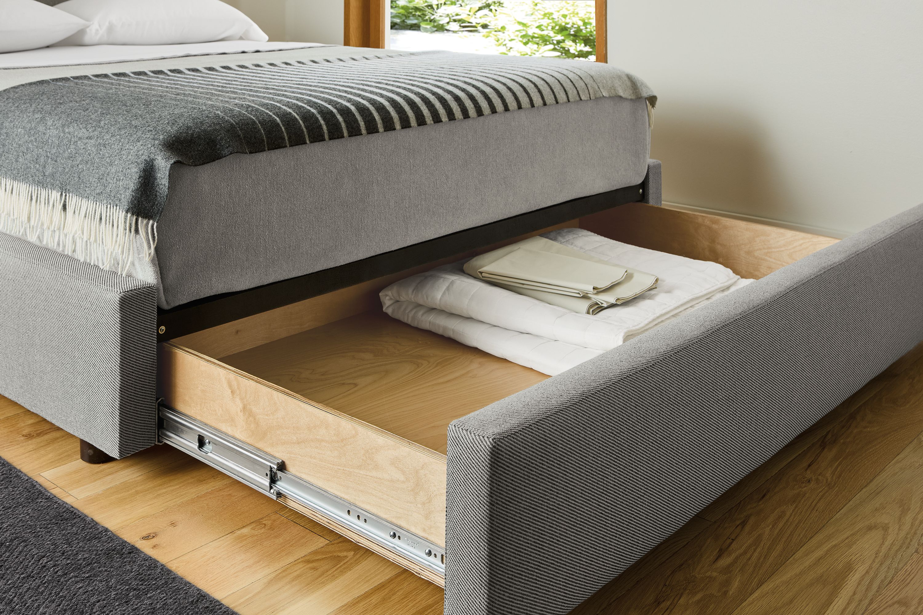 Bedroom with detail of wyatt queen storage bed in derry cement shown with storage drawer open.
