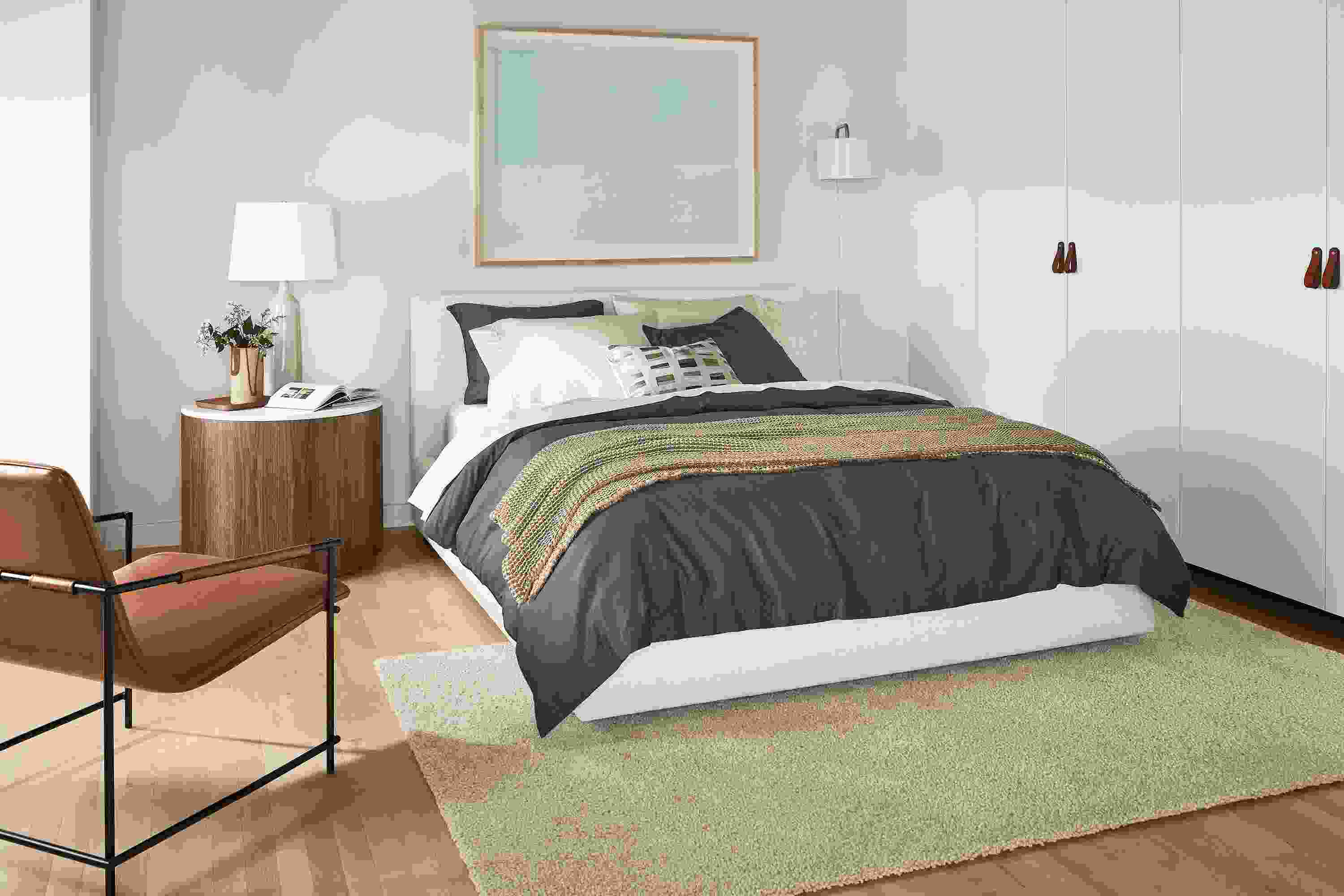 Bedroom with Wyatt queen bed in sumner ivory with Liam end table, Dina lounge chair, Arden low shag rug.