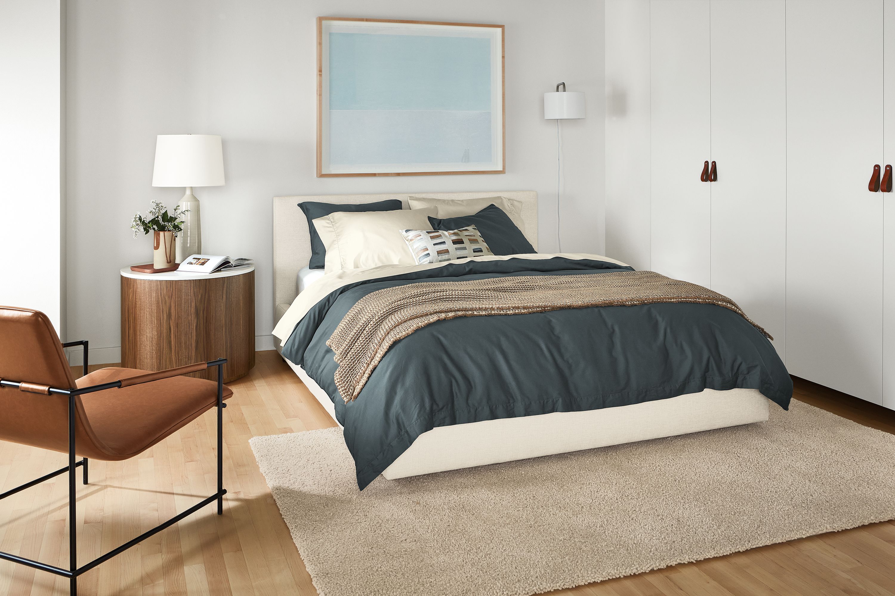 Bedroom with Wyatt queen bed in sumner ivory with Liam end table, Dina lounge chair, Arden low shag rug.