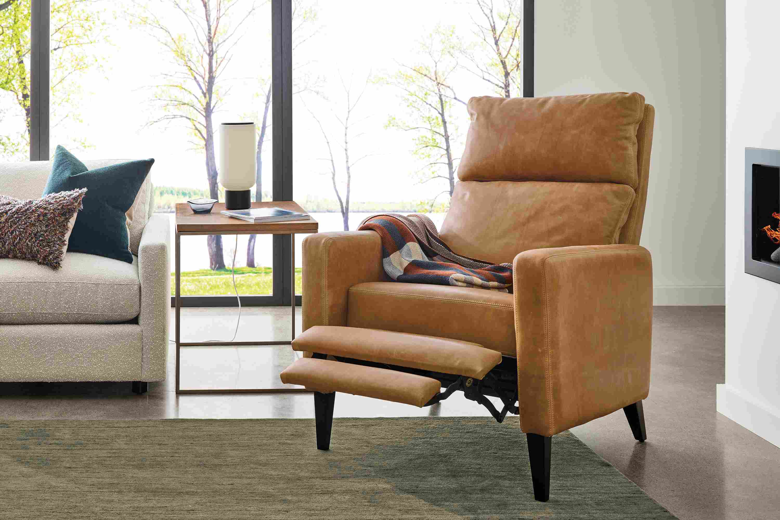 Living room with Wynton recliner in Sarto Camel leather shown reclined with footrest extended and Nomad rug in Olive.
