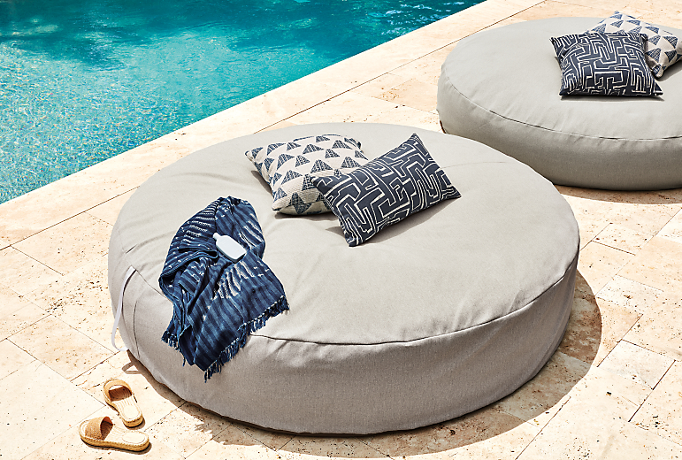 Two yamba 72-round bean bags in Mist grey with various outdoor pillows in ink on outdoor patio.