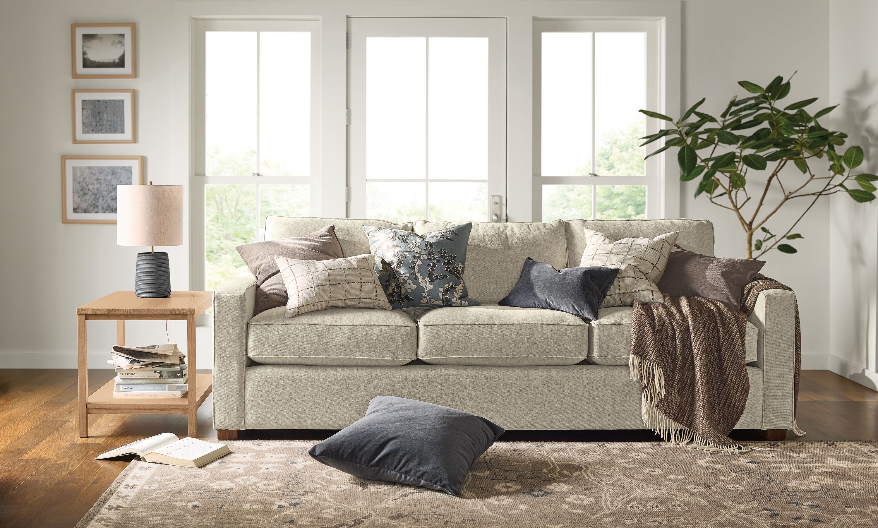 Living room with various throw pillows on a York sofa in Sumner Linen and Ophelia rug in pewter.